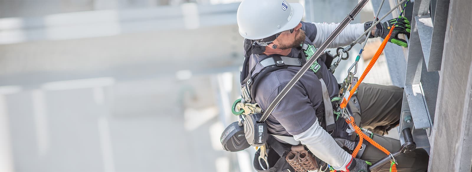 A S&B construction worked connected to safety lines working on the side of a building