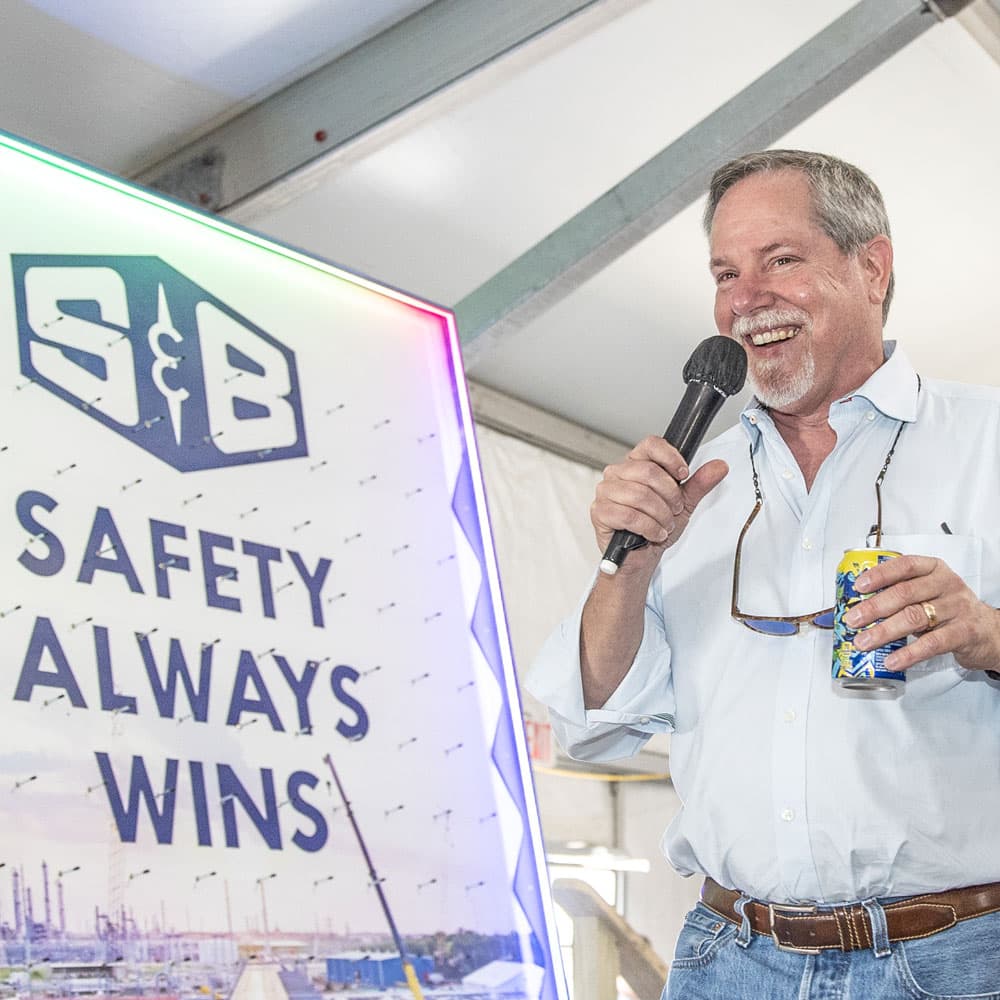 CEO J.W. Brookshite speaking next to an S&B safety poster