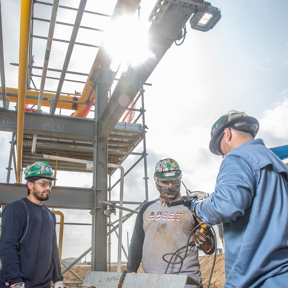 Three men in construction clothes and hardharts working