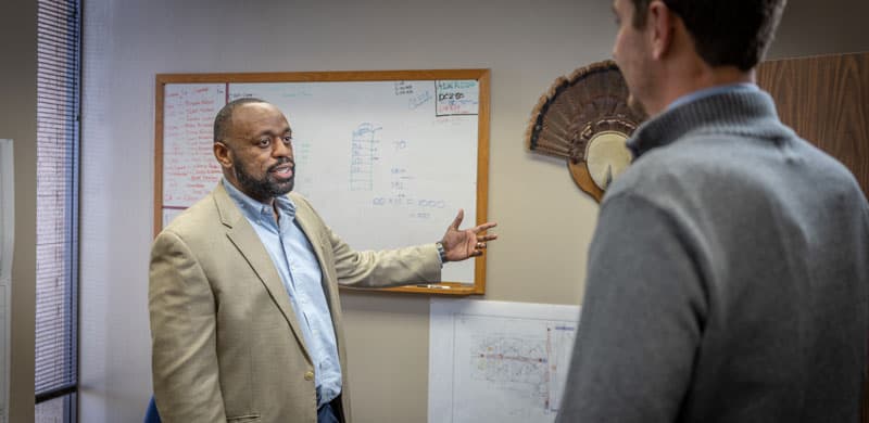 An S&B employee discussing work in front of a whiteboard