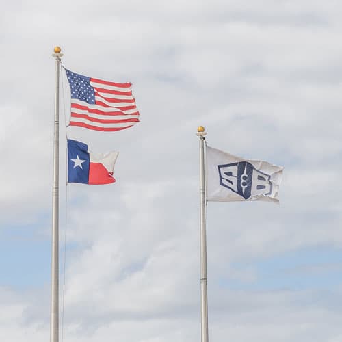 The S&B flag flying in the breeze next to the American and Texas flags