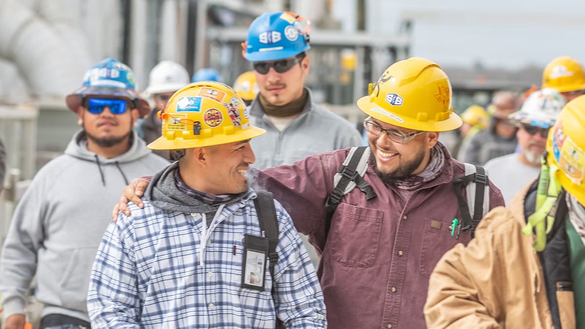 S&B construction workers with their arms around each other smiling