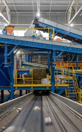 Materials on a platform going through a blue recycling conveyer belt