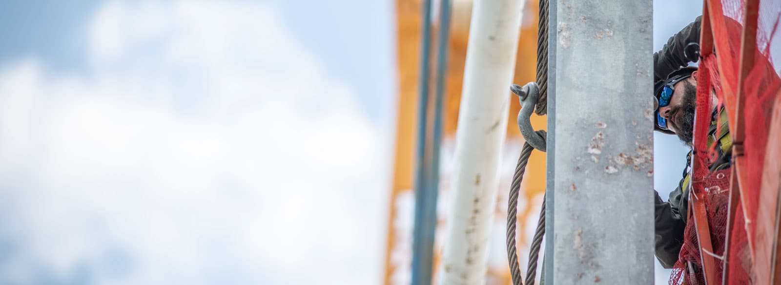 An S&B worker tying off lines on a pole at a construction site