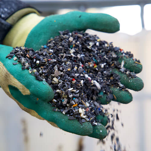 A pair of gloves holding recycled rubber scraps