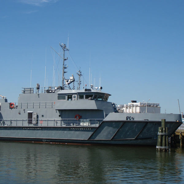 A grey U.S. Naval Academy Patrol Training Craft docked in a harbor