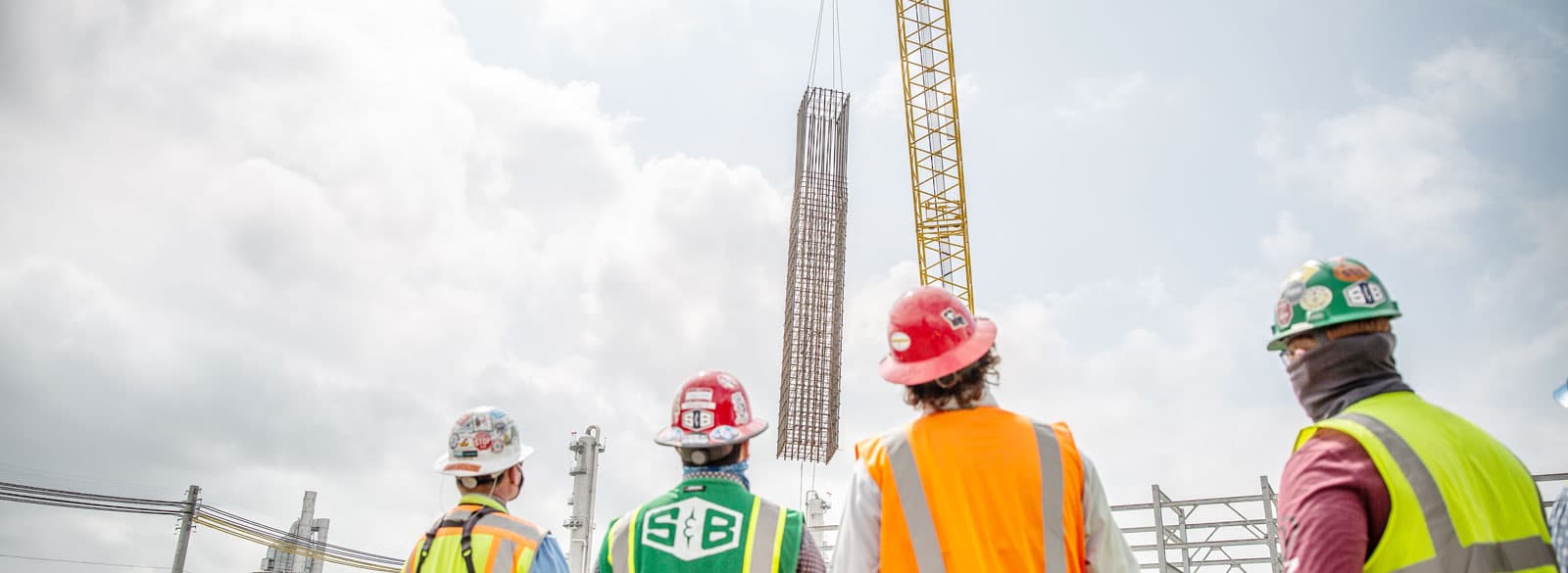 S&B construction workers watching a crane lift up rebar
